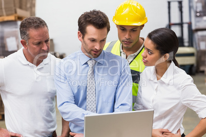 Warehouse managers and worker looking at laptop