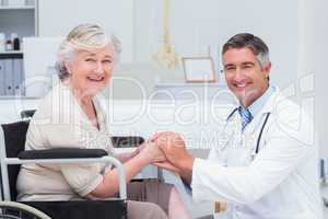 Happy doctor holding senior patients hands