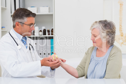 Male doctor assisting female patient to hold weight