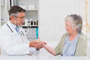 Male doctor assisting female patient to hold weight