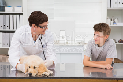 Smiling vet examining a dog with its owner