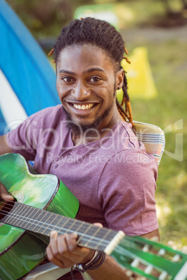 Happy hipster smiling at camera playing guitar