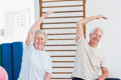 Senior couple doing stretching exercise in fitness studio