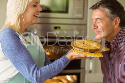 Mature blonde holding fresh pie with husband kissing her