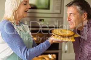 Mature blonde holding fresh pie with husband kissing her