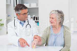 Doctor assisting patient to hold weight at table