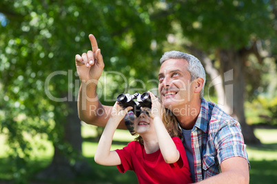 Happy little boy using binoculars with his father