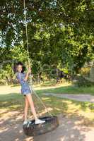 Pretty young woman in tire swing