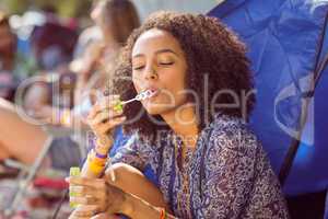 Carefree hipster blowing bubbles in tent