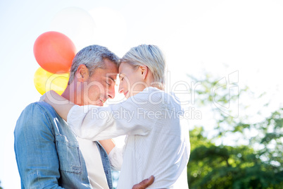 Cute couple hugging and holding balloons at the park