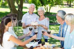 Happy couple holding cake at the park