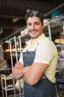 Smiling worker in apron with arms crossed