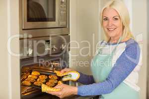 Woman taking tray of fresh cookies out of oven
