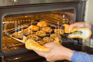 Woman taking tray of fresh cookies out of oven