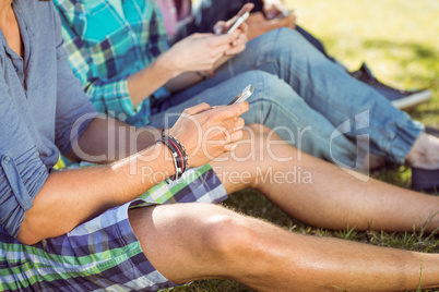 Hipsters sitting on the grass texting