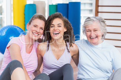 Happy female friends sitting together in gym