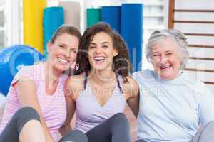 Happy female friends sitting together in gym