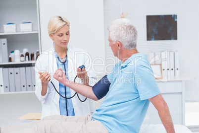 Doctor checking senior mans blood pressure