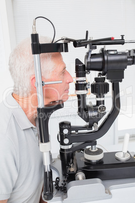 Senior patient looking into slit lamp