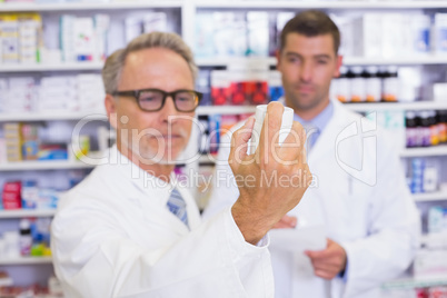 Pharmacist holding a box of pills while reading the label