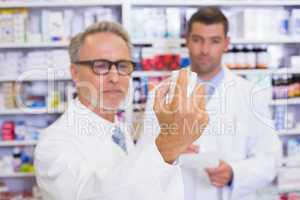 Pharmacist holding a box of pills while reading the label