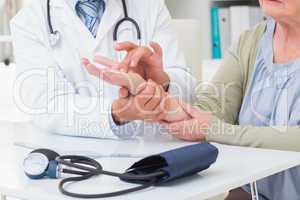 Doctor examining patients hand at table