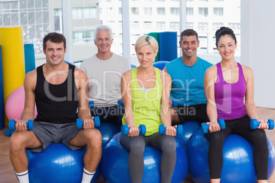 People sitting on balls and lifting weights in gym class