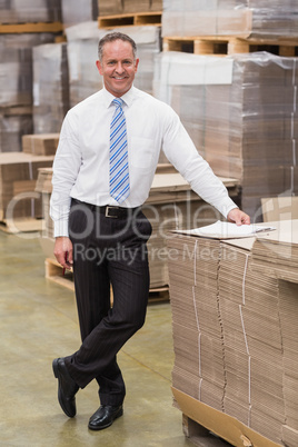 Smiling boss leaning on stack of cartons