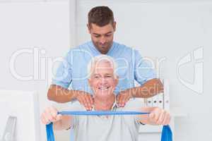 Physiotherapist assisting senior patient in exercising with resi