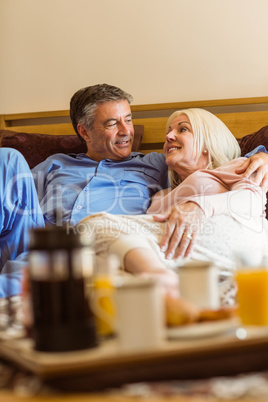 Happy mature couple having breakfast in bed