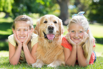 Happy sisters smiling at camera with their dog