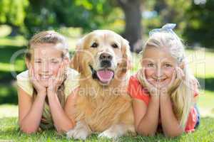 Happy sisters smiling at camera with their dog