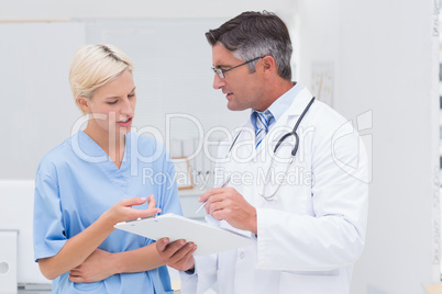 Doctor and nurse discussing over notes in clinic