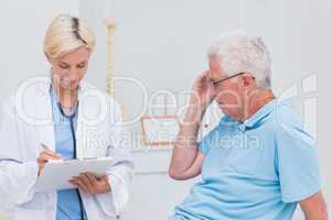 Doctor writing prescription for senior patient
