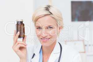 Confident female doctor holding medicine bottle