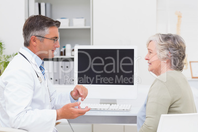 Male doctor conversing with senior patient at table