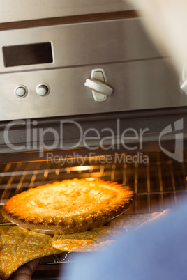 Woman taking fresh pie out of oven