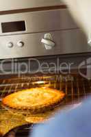 Woman taking fresh pie out of oven