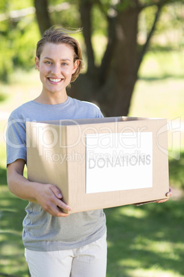 Happy volunteer in the park holding box