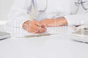 Doctor writing on clipboard