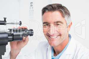 Happy optician using slit lamp in clinic