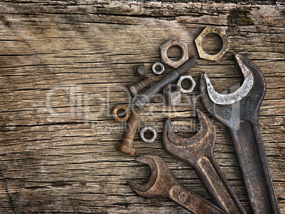 Old wrenches on the nuts and bolts on a wooden grungy background