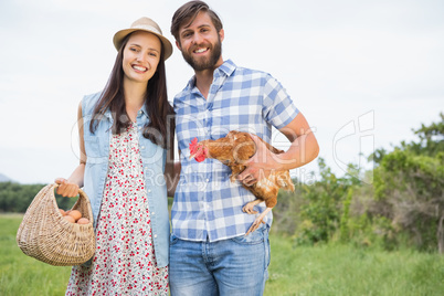 Happy farmers holding chicken and eggs