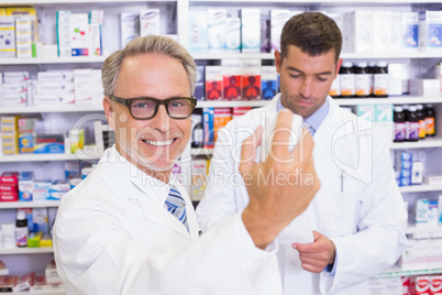 Smiling pharmacist holding a box of pills