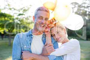 Happy couple holding balloons at the park