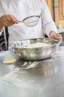 Baker working with sieve and bowl