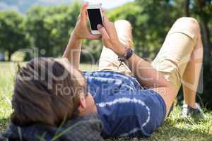 Handsome hipster using phone in park