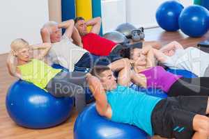 People stretching on exercise balls in fitness club