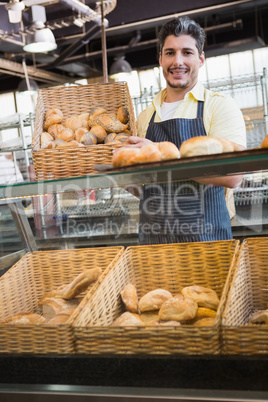 Portrait of smiling worker showing basket of bread