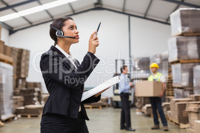 Warehouse manager wearing headset checking inventory
